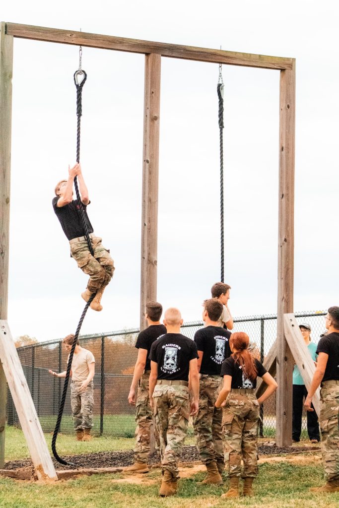 Two teams competing on the obstacle course rope climb