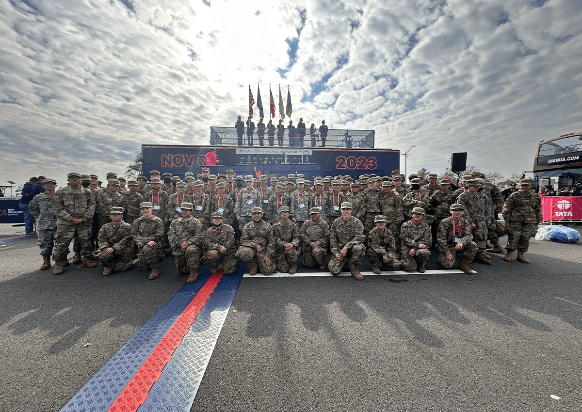 Fort Hamilton Tiger Battalion, gathered in front of the 2023 NYC Marathon announcer podium & Tiger Battalion Color Guard at attention