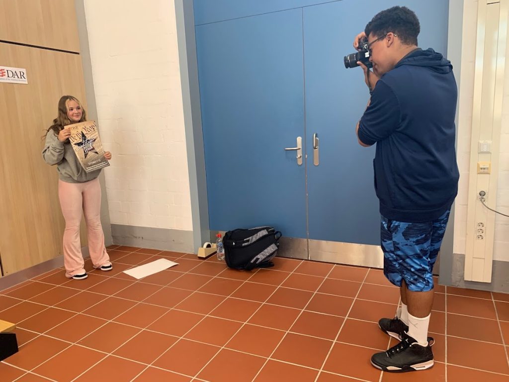 Cadet Abney takes a photo of a student with a Constitution Week poster.
