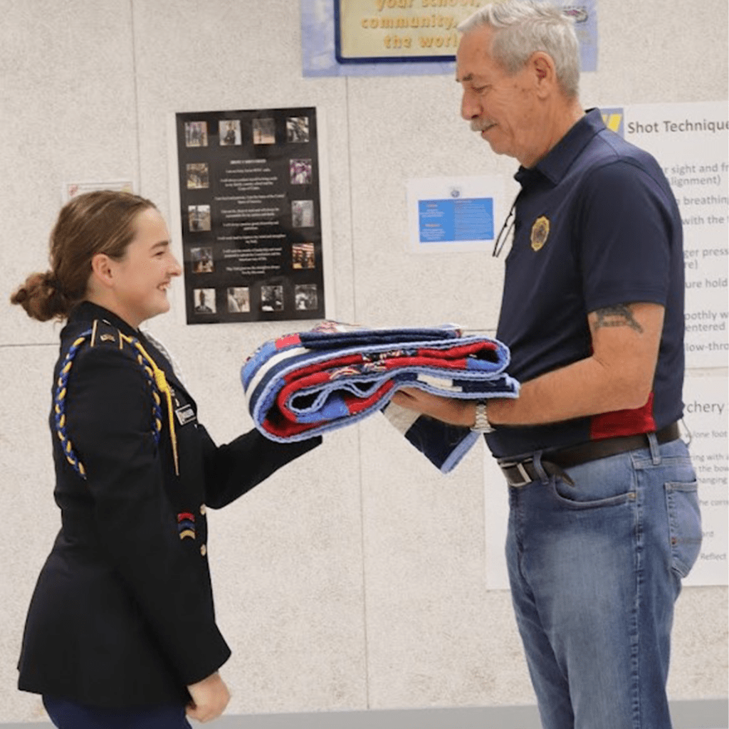 Cadet Woolever presents the Quilt of Valor to Mr. Mike Sherman
