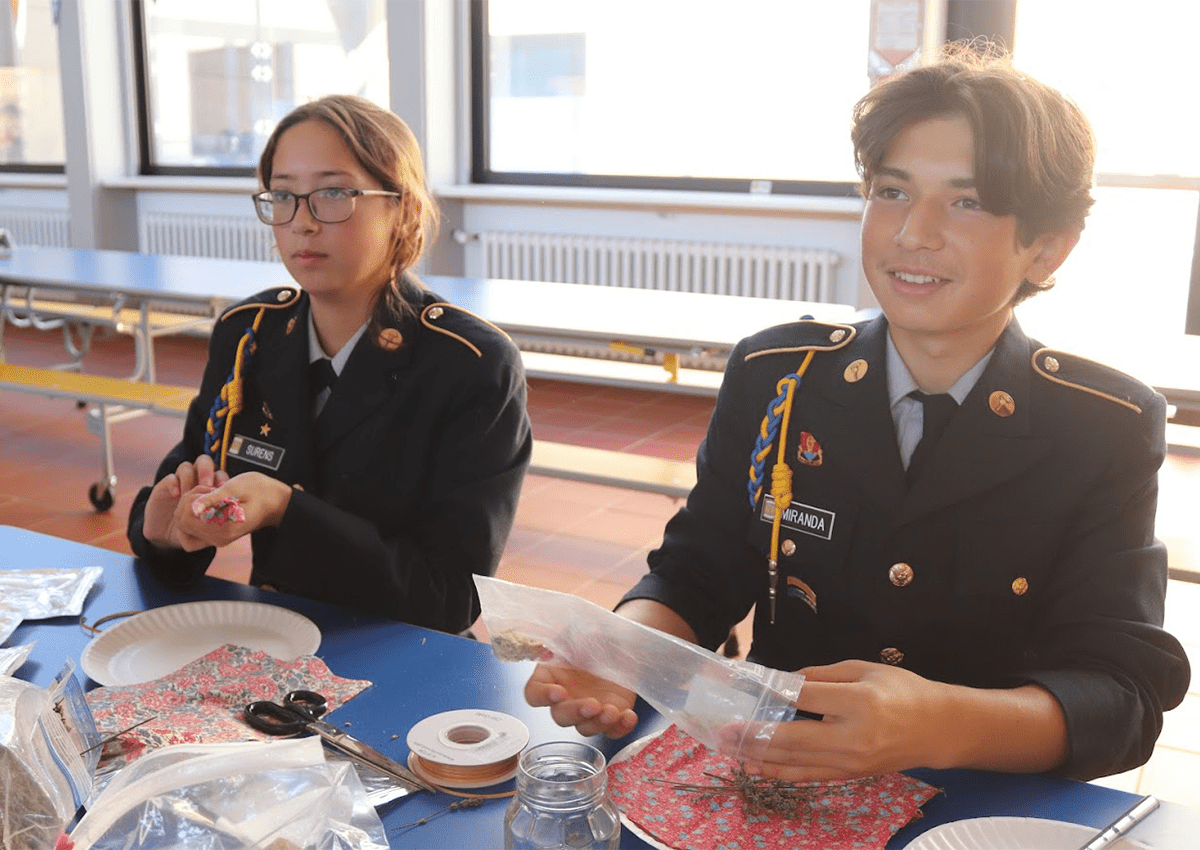 Cadets Kline and Aranha showing students how to make colonial sweet bags