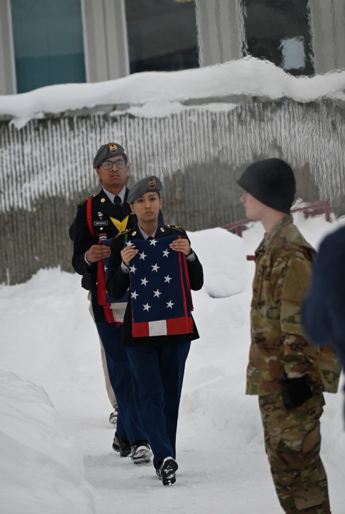 Cadets Gonzalez and Magana carrying flags to the retirement site outdoors to the site NCOIC Cadet Stone