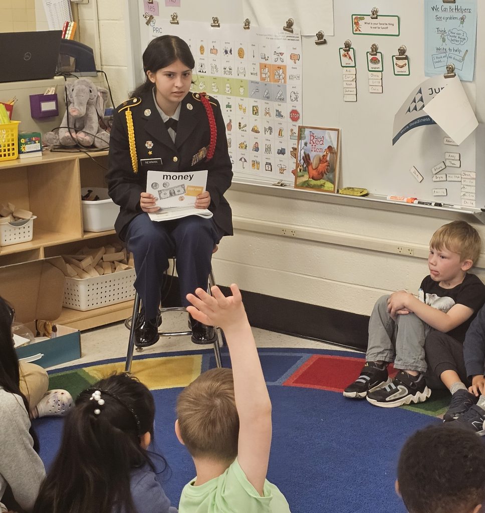 Cadet Whitney Newman presents a class on the different types of money to her Kindergarten Class.
