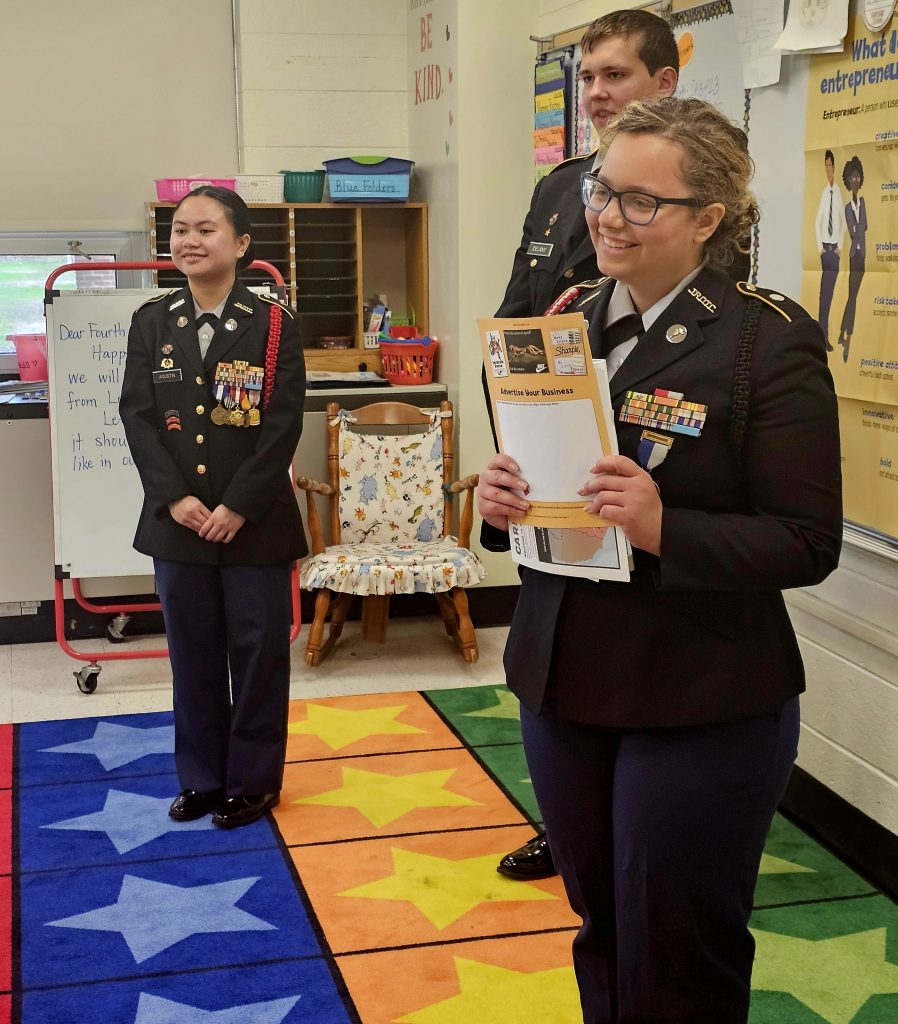Cadets Chelsea Agustin, Ryan Delany and Emily Flores teaching the 4th graders about advertising their business.
