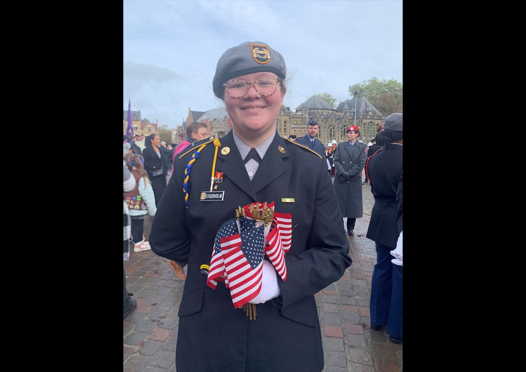 Photo Name: AnsbachVDT11 Names: Cdt/PFC Alaina Stockholm Photo Credit: MAJ (Ret) Madonna Roberts Caption: Cadet Stockholm distributing U.S. flags at the Poppy Parade in Ypres, Belgium